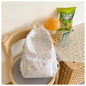 Detail of white backpack with blue star patterns and front pocket on wooden chair