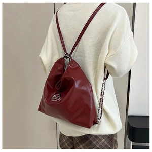 Détail du sac à dos en cuir verni bordeaux avec logo M en métal et bandoulière chaîne
