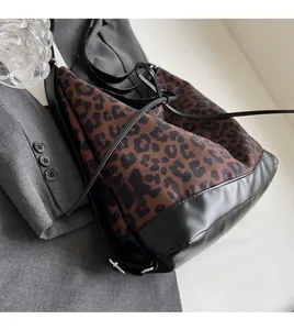Detail of leopard print canvas bucket bag with black leather trim on a grey suit jacket