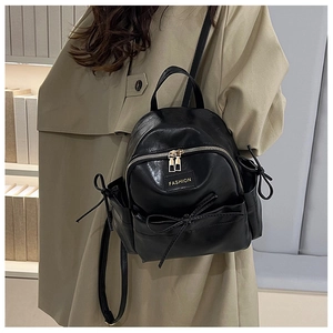 Gros plan du mini sac à dos en cuir noir avec un nœud élégant et une fermeture éclair polie