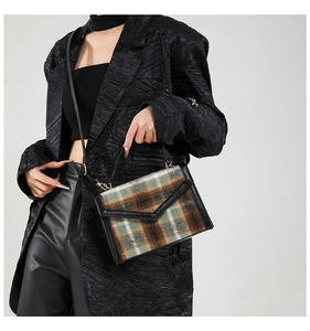 Détail d'un sac vintage en laine à carreaux verts et cuir noir porté par un mannequin