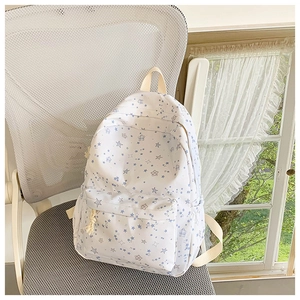 Detail of white star print backpack with front zipper pocket on a white office chair