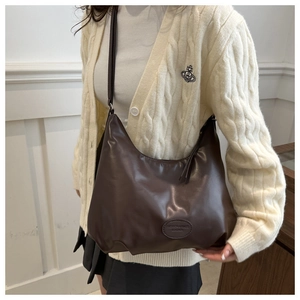 Detail of dark brown leather tote bag showing the embossed logo and textured finish