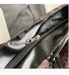 Detail of smooth gold zipper closure on leopard print tote bag with black faux leather trim