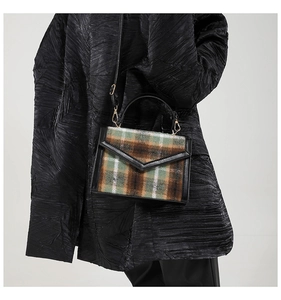 Détail du sac en laine à carreaux vintage avec bordure en cuir et bandoulière réglable