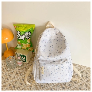 Close-up of white canvas backpack featuring blue star patterns and woven zipper pulls