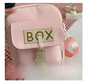Detailed shot of pink canvas crossbody bag with cute bear pendant and leather patch