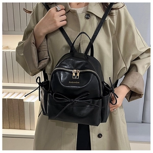 Détail d'un mini sac à dos noir en cuir PU avec un nœud décoratif et des fermetures éclair dorées