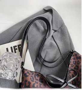 Detail of leopard print tote bag with black leather handles and decorative side bow tie