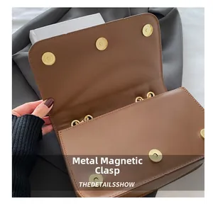 Close-up of golden magnetic hardware snaps on a brown leather chain flap bag