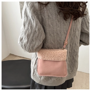 Detail of pink faux leather bag featuring cream faux shearling flap and metal buckle