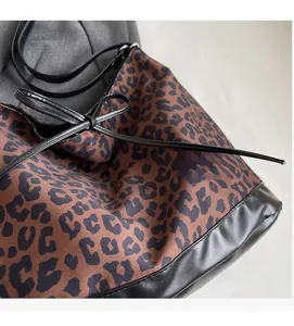 Detail of leopard print tote bag with black faux leather base and drawstring ribbon