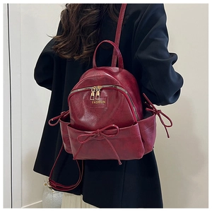 Détail d'un petit sac à dos en cuir PU bordeaux avec nœuds décoratifs et logo doré
