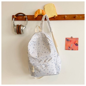 Detail view of white backpack with light blue star patterns and side pockets