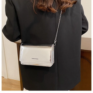 Détail du sac bandoulière argenté métallisé avec chaîne sur un blazer noir