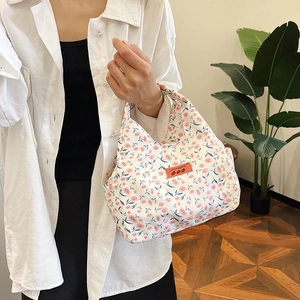 Floral canvas lunch bag with pink flower patterns and orange label shown by a model