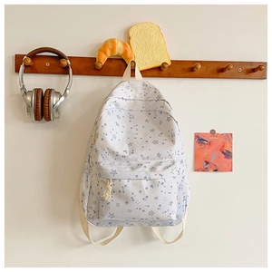 Detailed view of the light canvas backpack with blue star patterns hanging on a hook