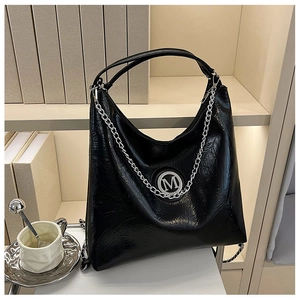 Détail d'un cabas noir en cuir brillant froissé avec un emblème M argenté chic
