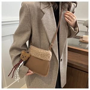 Detail view of winter furry bucket bag with plush bear charm and faux fur patchwork texture