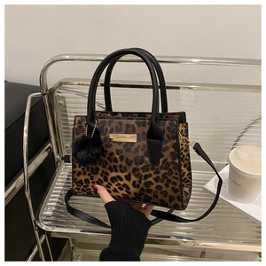 Detailed view of leopard print tote bag with gold metal buckle and faux fur pompom charm