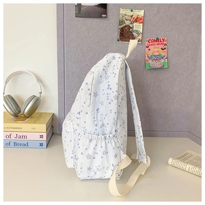 Close-up of white backpack with blue star patterns showing elastic side pocket and soft strap