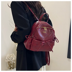 Détail du mini sac à dos en cuir bordeaux avec un nœud délicat et des fermetures dorées