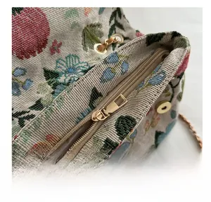 Close-up of smooth gold zipper and floral jacquard fabric on a women crossbody bag
