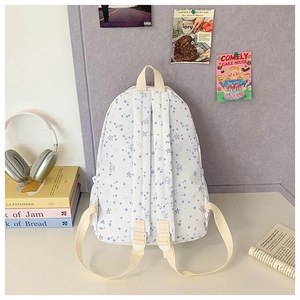 Detailed view of white canvas star-patterned backpack in a cozy study desk setting