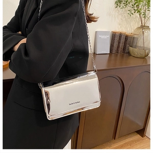 Zilveren crossbodytas met spiegeleffect en ketting gedragen op een zwarte blazer