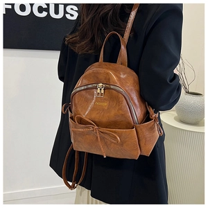 Détail d'un sac à dos en cuir PU marron avec fermeture éclair dorée et nœud décoratif
