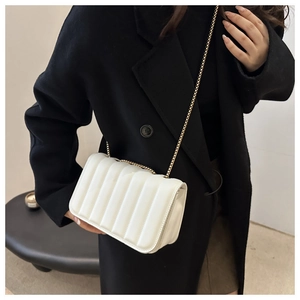 Detail of white quilted texture and elegant gold chain strap on small crossbody bag