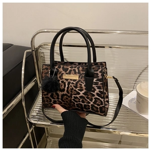 Detail view of leopard print doctor bag with black handles and fluffy pompom charm