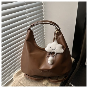 Close-up of brown faux leather hobo bag with cloud plush charm and embossed lettering