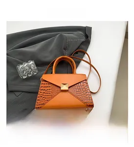 Detail of orange trapezoid bag with crocodile texture panels and gold metal lock clasp