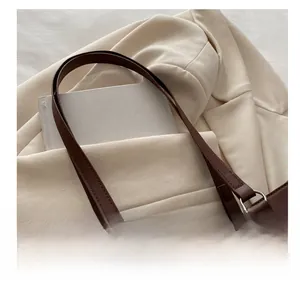 Close-up of brown leather tote bag with silver bow hardware and reinforced handles