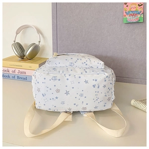 Detailed view of white floral backpack with blue star patterns in a campus setting