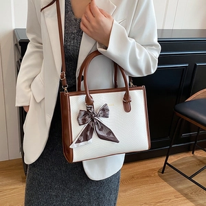 Elegante borsa a mano bicolore con sciarpa di seta e scritte dorate in interno moderno