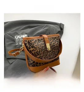 Detail view of leopard print bucket bag with gold clasp and brown leather trim