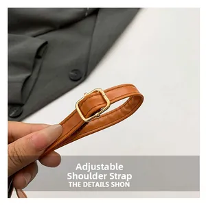 Detail of adjustable caramel leather shoulder strap with a polished gold metal buckle