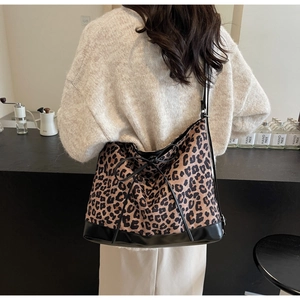 Close-up of leopard print tote bag with black leather straps and a decorative bow tie