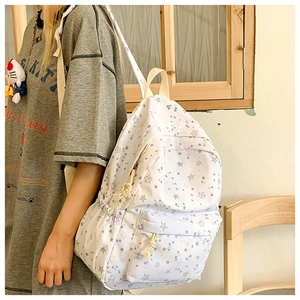 Detail view of a white canvas backpack with blue star patterns and large capacity main pocket
