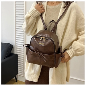 Détail du mini sac à dos en cuir café foncé avec décoration nœud et zip métallique