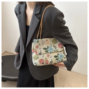 Close-up of floral jacquard texture and metallic chain strap on a crossbody bag