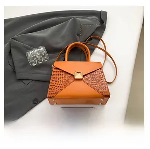 Detailed close-up of orange leather handbag with gold hardware and croc-embossed texture
