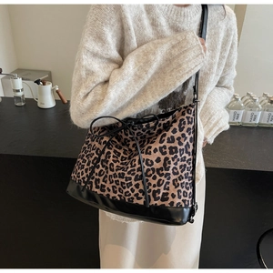 Leopard print tote bag with black leather base and slim straps in indoor casual setting