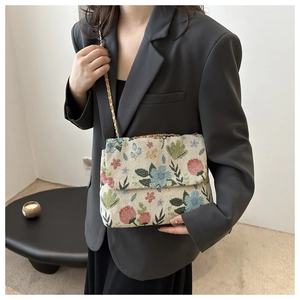 Detail of floral embroidery and gold chain strap on the corduroy crossbody bag