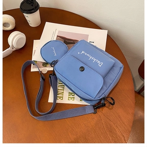 Detail of blue canvas messenger bag set with dachshund text and matching round coin purse