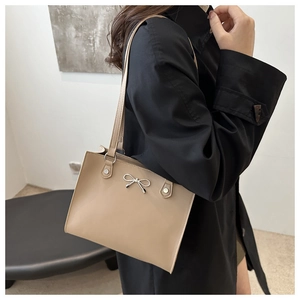 Beige PU leather tote bag featuring a silver metal bow detail and long shoulder straps