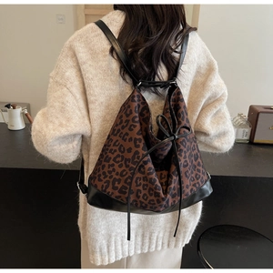 Detail shot of leopard print backpack with black leather base and drawstring ribbon detail