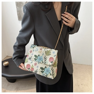 Detailed close-up of corduroy crossbody bag with colorful floral embroidery and gold chain